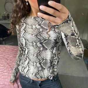 Ormmönstrad topp från Gina Tricot - Säljer en snygg ormmönstrad topp från Gina Tricot i storlek S. Toppen har långa ärmar och ett coolt mönster i svart och beige. Perfekt för att ge din outfit en trendig touch💕❣️