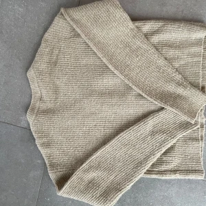 Beige stickad kofta från LMTD - Säljer en mysig beige stickad kofta från LMTD. Koftan har en v-ringad design med knappar framtill och långa ärmar. Perfekt för kyligare dagar och lätt att matcha med olika outfits.