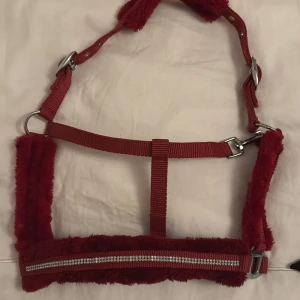 Rött ponnygrimma med glitterdetaljer - Snygg röd ponnygrimma med mjukt foder och glittrande silverdetaljer. Perfekt för att ge din ponny lite extra stil. Justerbar och bekväm passform. Inte ens testad, NY!