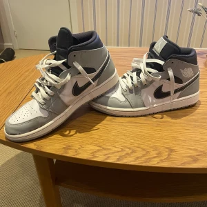 Nike Air Jordans i light  - Säljer ett par Nike Air Jordans i grått och vitt med klassisk snörning. Skorna har en stilren designhög ankelkrage för extra stöd. Vi tåspättsarna finns lite färgtapp, men går enkelt att fixa till, annars i fin skick, mer bilder skickas om man är intresserad. Ingen låda.
