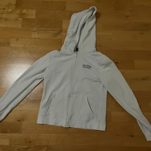 Vit hoodie från Polo Jeans Co. Ralph Lauren - Säljer en stilren vit hoodie från Polo Jeans Co. Ralph Lauren. Den har en dragkedja framtill och en klassisk huva. Tillverkad i bomull med en liten del elastan för extra komfort. Den är i fint skicka 