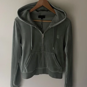 Grönt juicy couture sett - Säljer mitt juicy sett då de inte kommer till användning. Köppt nytt sommaren 2022, användes senast för ca 1 år sen. Metallet på byxornas snören är av och de finns små märken ca 5 st på hela setet(bild finns vid förfrågan). Byxorna är i storlek XS och tröjan i storlek M.