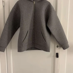 Grå Jacka från Zara - Säljer en grå Jacka från Zara med dragkedja och fickor framtill. Perfekt för en avslappnad stil. Den har långa ärmar och en bekväm passform.