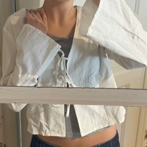 Vit knytblus linne - Säljer en stilren vit linne blus med knytning framtill. Blusen har långa ärmar och en luftig passform. Aldrig använd