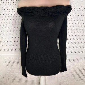 Svart offshoulder tröja med flätad detalj - Snygg svart offshoulder tröja med en unik flätad detalj runt halsen. Tröjan är stickad och har långa ärmar samt en ribbad nederkant som ger en fin passform. Perfekt för en stilren look.