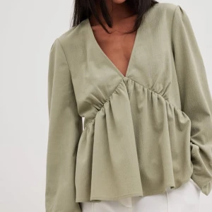 Olivgrön blus med v-ringning - Söt olivgrön blus med v-ringning och volangdetaljer. Blusen har långa ärmar och är i ett skönt material. Perfekt för både vardag och speciella tillfällen. Passar nu till våren!!😍Helt ny!!! Nypris 400kr🤍