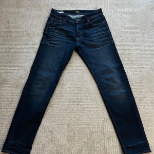 Mörkblå jeansbyxor NYA SKICK - Snygga mörkblå jeansbyxor med en klassisk femficksdesign. De har en knapp och dragkedja framtill och är perfekta för en stilren look. Passformen är normal och de är tillverkade i ett slitstarkt material. Endast använda 3 gånger rak passform