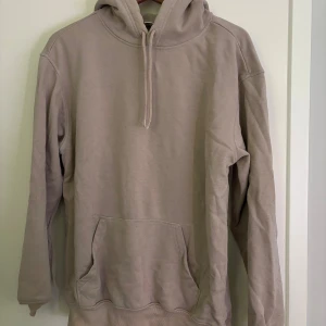 Beige hoodie - Säljer en stilren beige hoodie med känguruficka och justerbar huva. Perfekt för en avslappnad look. Passar bra till både jeans och mjukisbyxor.