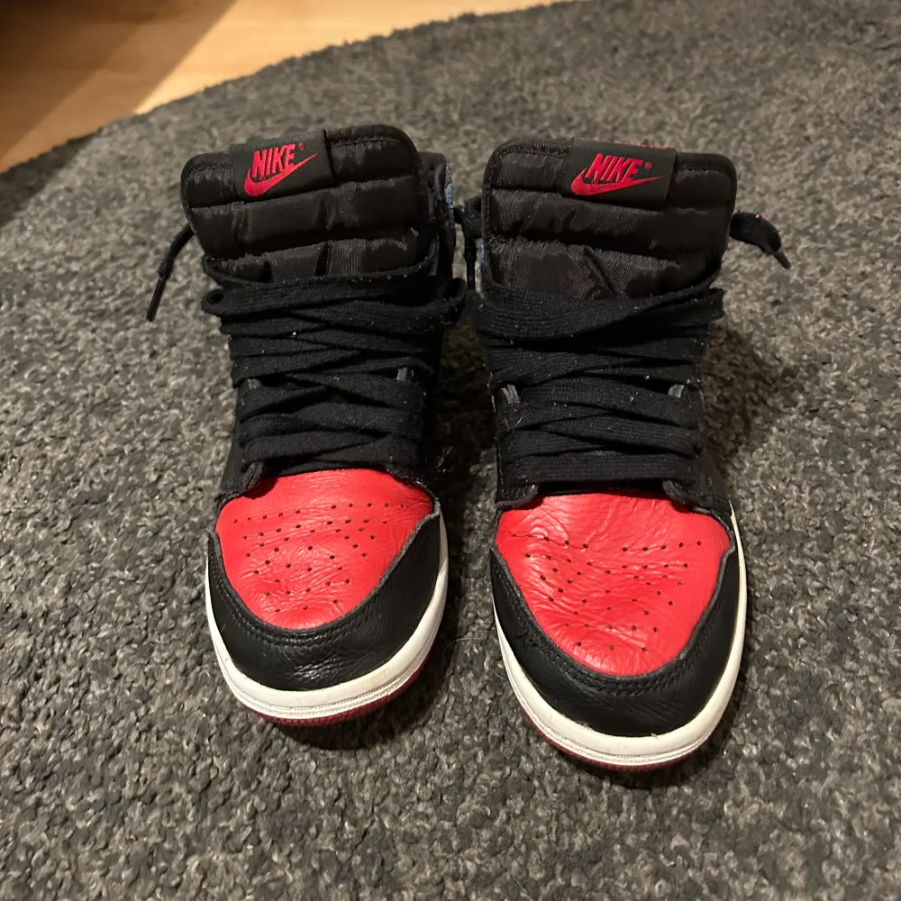 Snygga Nike Air Jordans med en cool färgkombination av svart, röd och blå. Skorna har klassisk snörning och en hög design som ger extra stöd. Perfekta för dig som vill ha en stilren och sportig look.. Kengät.