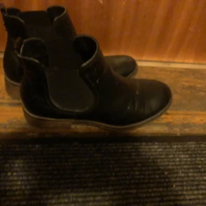 Svarta Chelsea boots - Snygga svarta Chelsea boots med elastiska paneler på sidorna för enkel på- och avtagning. Perfekta för både vardag och mer uppklädda tillfällen. Klassisk design med låg klack och rundad tå.