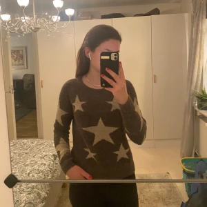 Gråbrun stickad tröja med stjärnor från ONLY - Säljer en gråbrun stickad tröja från ONLY med stora vita stjärnor som mönster. Tröjan har långa ärmar och en rund halsringning. Perfekt för en mysig och stilren look. 🌟