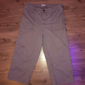 Beige byxor från Holly & Whyte by Lindex - Säljer ett par baggy beige byxor från Holly & Whyte by Lindex. Byxorna har en avslappnad passform med stora framfickor och knappar bak. Perfekta för en casual look.