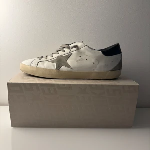 Vita sneakers från Golden Goose - Ett par extremt snygga Golden Goose i strl 44.           Har inte använt de så jättemycket då de har varit lite stora. Väldigt bra skick 8,7/10 någon defekt på hälen men det är inget som man märker. Vid frågor så är det bara att skriva😊Priset är inte fast hugget i sten🪨! Allt og medföljer