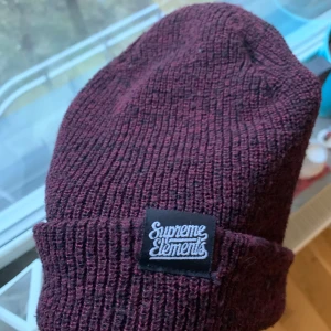 Vinröd mössa Supreme Elements London - Vinröd mössa från indiemärket Supreme Elements London (Instagram @supremeelements). Lagad på insidan - syns inte på utsidan. Unisex. 55% polyester 45% akryl. Fler bilder kan skickas på begäran!