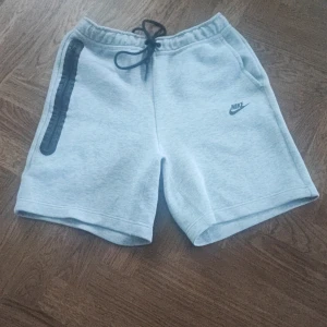 Nike tech shorts - Snygga grå shorts från Nike med svart snörning i midjan och en diskret logga på benet. Knappt andvända dom är M men passar L