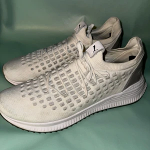 Vita sneakers från Puma - Snygga vita sneakers från Puma med en modern design och stickad ovandel. Skorna har snörning och en bekväm sula med IGNITE-teknologi för extra dämpning. Perfekta för en stilren look.