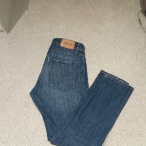 Blå jeans från Jack & Jones - Säljer ett par blå jeans från Jack & Jones i relaxed fit. De har en klassisk femficksdesign och en bekväm passform. Perfekta för en avslappnad stil. 29/ 32