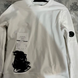 Vit sweatshirt från C.P. Company - Säljer en stilren vit sweatshirt från C.P. Company. Tröjan har en rund halsringning och en diskret logotyp på ärmen. Perfekt för en avslappnad och trendig look. Använd en gång. Kvitto finns med. Pris kan diskuteras!!!
