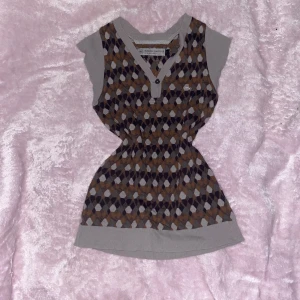 Mönstrad ärmlös topp från Rudolf Dassler - Snygg ärmlös topp från Rudolf Dassler med ett unikt geometriskt mönster i brunt, beige och svart. Toppen har en knappdetalj vid halsen och ribbade kanter. Använd gärna köp nu💗🐾