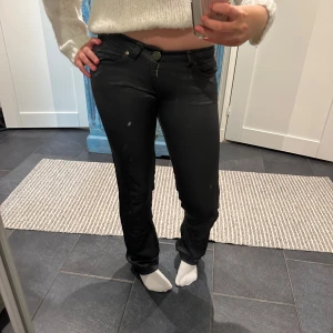 Svarta lågmidjade byxor  - Snygga svarta silkes/skin byxor med låg midja och en tight passform. Byxorna har klassisk design och stängs med dragkedja och knapp. Perfekta för en stilren look. Dessa är från ett indiskt märke vet inte vart det är köpa… trendiga och super fina. Tyvärr lite slitna längst ner men det är inget som syns. Jag är 171 som referens!🥰Det är en fläck på spegeln INTE byxan!