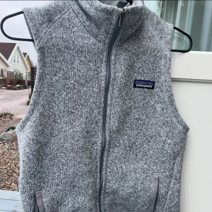 Grå patagino väst används 3 till 2 gången för att den är för liten  - Säljer en grå fleeceväst från Patagonia med dragkedja framtill. Västen har en hög krage och två fickor med dragkedja. Perfekt för lager-på-lager under kyliga dagar.
