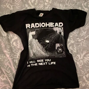 Svart Radiohead t-shirt - Cool svart t-shirt med Radiohead-tryck och texten 'I will see you in the next life'. Perfekt för fans av bandet. T-shirten har en klassisk passform och är gjord av bomull för en bekväm känsla.