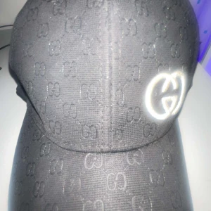 Svart G keps - Snygg svart keps med diskret mönster och broderad logotyp framtill. Perfekt för en stilren look. Kepsen har en justerbar passform och är tillverkad i ett slitstarkt material.