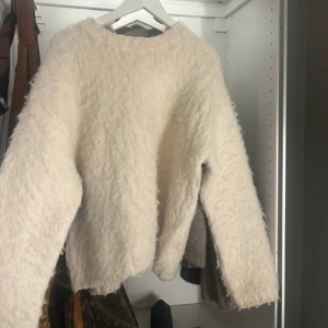 Vit fluffig tröja från H&M - Mysig vit fluffig tröja från H&M. Perfekt för kyliga dagar med sin varma och mjuka känsla. Tröjan har långa ärmar och en rund halsringning.