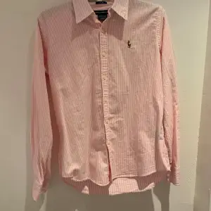 Det här är en rosa vit Ralph lauren skjorta  som är i väldigt bra skick 9/10 Som jag säljer för att den blev för liten   