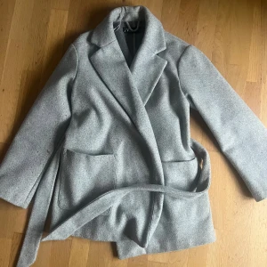 Kort kappa  - Kort grå kappa med avtagbart skärp, lite nopprig på vissa delar 💫💫