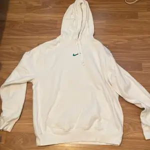 Säljer en snygg vit hoodie från Nike i storlek M. Den är i perfekt skick 10/10 med en stor Nike-logga i blått på ryggen och en mindre på framsidan. Hoodien är i standard passform och har en stor ficka framtill. Perfekt för både vardag och träning!