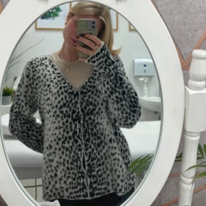 Leopard kofta från Jaded London - Säljer en mysig kofta från Jaded London i svart och vit med leopardmönster. Koftan har en v-ringad design och knappar framtill. Perfekt för att hålla sig varm och stilren.