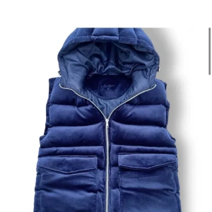 Manchester väster den vendiera - Snygg blå quiltad dunväst med dragkedja och praktisk huva. Västen har två fickor framtill för extra förvaring. 10/10 helt ny 