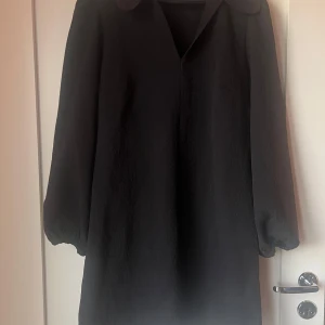 Svart klänning från Samsøe Samsøe - Elegant svart klänning från Samsøe Samsøe med långa ärmar och en klassisk krage. Perfekt för en stilren look.