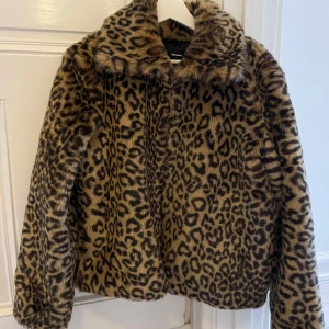 Leopardmönstrad pälsjacka  - Snygg och trendig leopardmönstrad pälsjacka. Jackan har en klassisk krage och långa ärmar. 