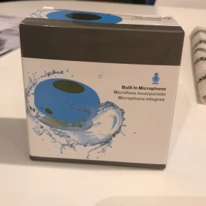 Vattentålig högtalare - Liten blå högtalare med sugpropp på baksidan för att sättas fast i duschen. Helt ny. Ej öppnad eller testad. På/av knapp, mikrofon så du kan prata i telefon. Och högtalare för att kunna lyssna på musik. Knappar för att byta låtar, sätta på och av musiken och svara och lägga på samtal. Pris kan diskuteras lite. Frakt betalas av köpare. 