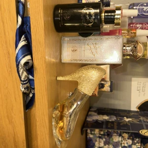 Tre parfymer i olika flaskor - Säljer tre unika parfymer. En svart flaska med gulddekorationer, en silverfärgad flaska med orientaliskt mönster och en i form av en högklackad sko med guldglitter. Perfekt för den som vill ha något speciellt i sin samling.