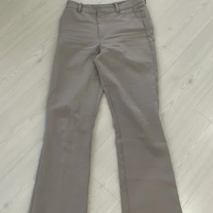 Beige kostymbyxor från Bik Bok - Snygga beige kostymbyxor från Bik Bok i storlek 38. Byxorna har en klassisk design med raka ben och bälteshällor. Perfekta för en stilren look.