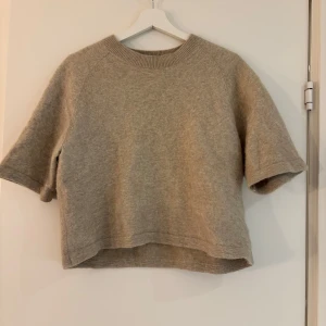 Beige tröja från & Other Stories - Säljer en stilren beige tröja från & Other Stories. Tröjan har korta ärmar och en rund halsringning. Perfekt för en avslappnad look. Tröjan är i bra skick och sann i storleken.