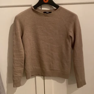 Beige kashmirtröja från Uniqlo - Säljer en supermjuk beige kashmirtröja från Uniqlo. Perfekt för kyliga dagar med sin klassiska design och långa ärmar. Tröjan har en rund halsringning och ribbade kanter för en stilren look. Ett måste i garderoben för den som älskar komfort och stil.
