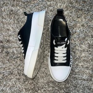 Svarta sneakers från Dolce & Gabbana - Stilrena svarta sneakers från Dolce & Gabbana med vit sula och snörning. Skorna har en tydlig logotyp på sidan och en dekorativ sula med mönster. Perfekta för en trendig look.