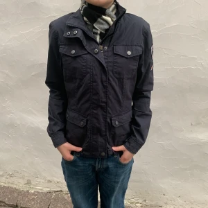 Mörkblå jacka från Berkeley - Säljer en mörkblå jacka från Berkeley. Jackan har en dragkedja och knappar framtill samt flera praktiska fickor. Perfekt för höst och vår. Priset kan diskuteras