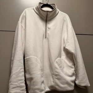 Vit fleece  - Mysig vit fleece från ASOS Design med halv dragkedja och hög krage. Perfekt för kyliga dagar. Den har en avslappnad passform och praktiska fickor framtill.
