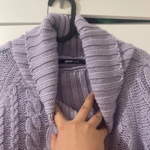 Ljuslila stickad polotröja från Gina Tricot - Mysig ljuslila stickad polotröja från Gina Tricot med flätmönster. Tröjan har en hög polokrage och är croppad med långa ärmar. Perfekt för kyliga dagar!