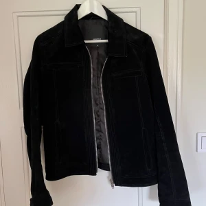 Svart mockajacka från Rockandblue - Snygg svart mockajacka från Rockandblue i storlek M. Jackan har en dragkedja framtill och stilrena detaljer. Perfekt för en cool look.