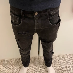 svarta replay jeans - unika svarta replay hyperflex anbass jeans med slitna och washed detaljer i storlek 29x30 