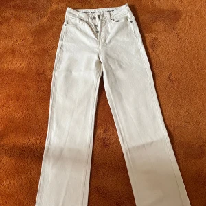 Vita jeans som är högmidjade - Säljer ett par stilrena vita jeans med regular wide passform. De har en klassisk design med knappar i midjan. Säljer pågrund av storlek, inga fläckar.