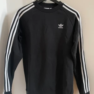 Svart sweatshirt från Adidas - Svart sweatshirt från Adidas i storlek XS. Väldigt fint skick, använd ett fåtal gånger!