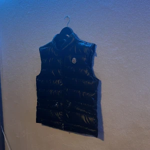 Svart dunväst från Moncler - Svart moncler gui väst i storlek 1!  Perfekt för kyligare dagar när du vill hålla stilen! Helt skadefri förutom att de är lite problem med kedjan, annars helt perfekt väst för dig som gillar märkeskläder!