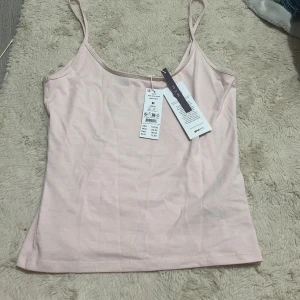 Ljusrosa linnetopp från Gina tricot - Säljer en ljusrosa linnetopp från gina tricot med smala axelband. Perfekt för varma dagar eller som ett basplagg i garderoben. Toppen är i ett mjukt och bekvämt material.